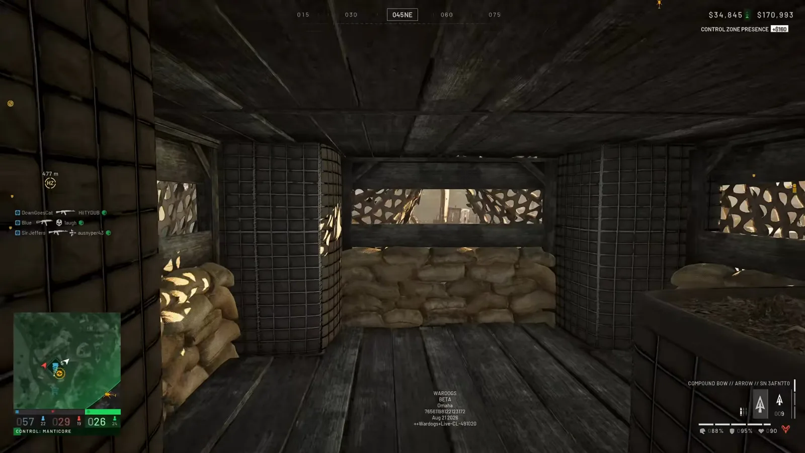 Compound bow aimed through a camo-net firing slit inside a sandbagged WARDOGS bunker during a FOB clear-out